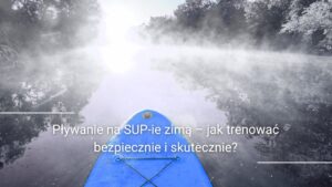 Pływanie na SUP-ie zimą– osoba na desce SUP na spokojnym jeziorze zimą, natura wokół, mgła nad wodą.